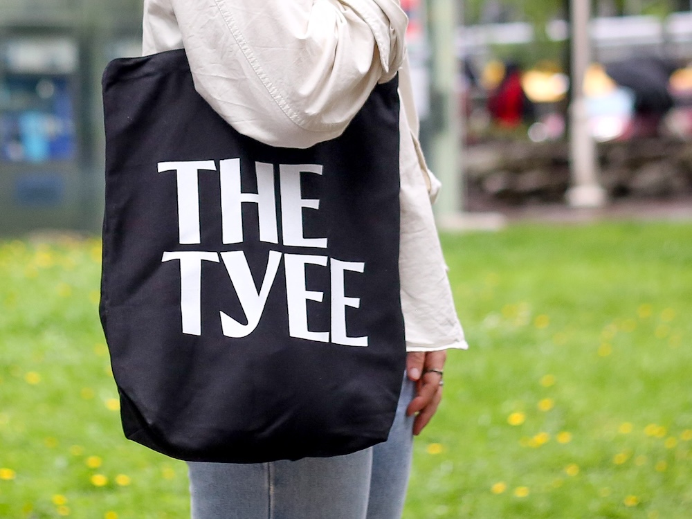 A person wears a black tote bag that says &lsquo;The Tyee&rsquo; in white lettering.