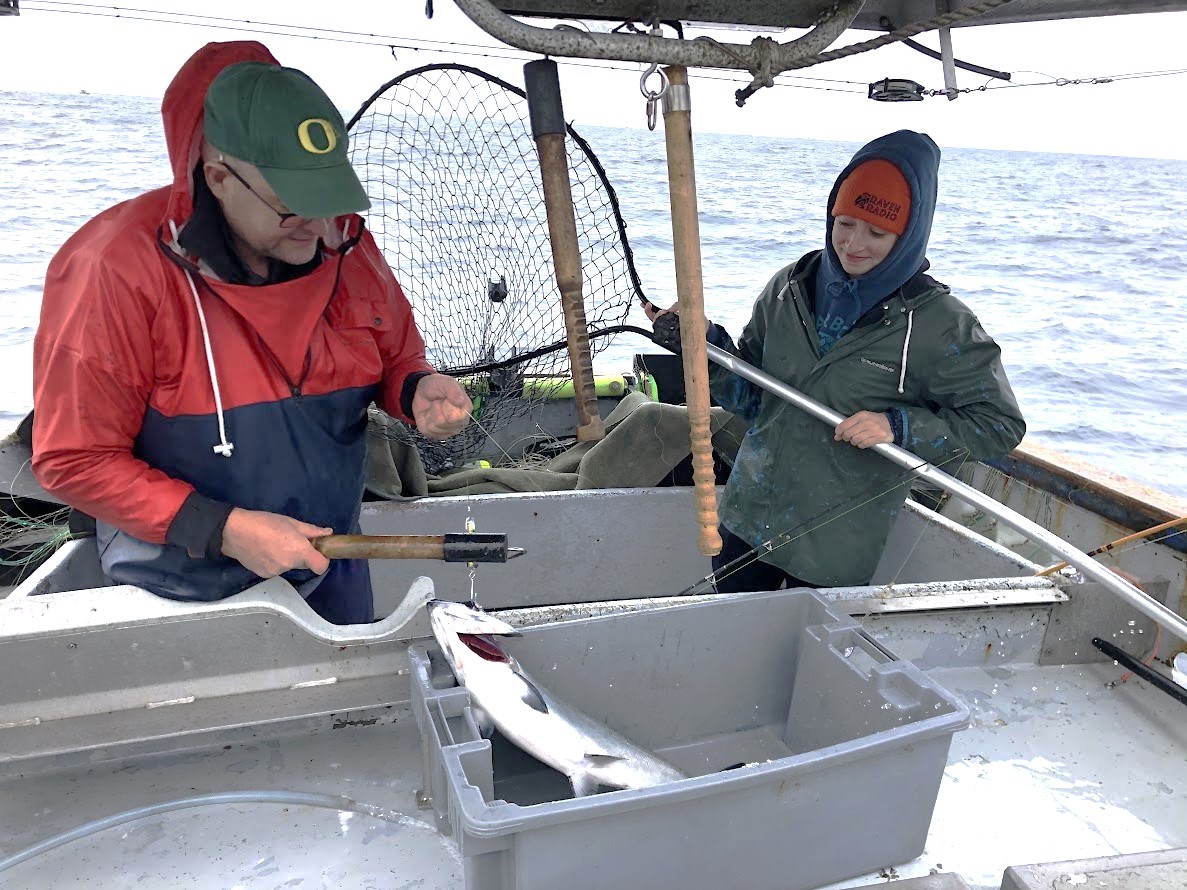 A young woman and an older man at work on a fishing boat at sea.