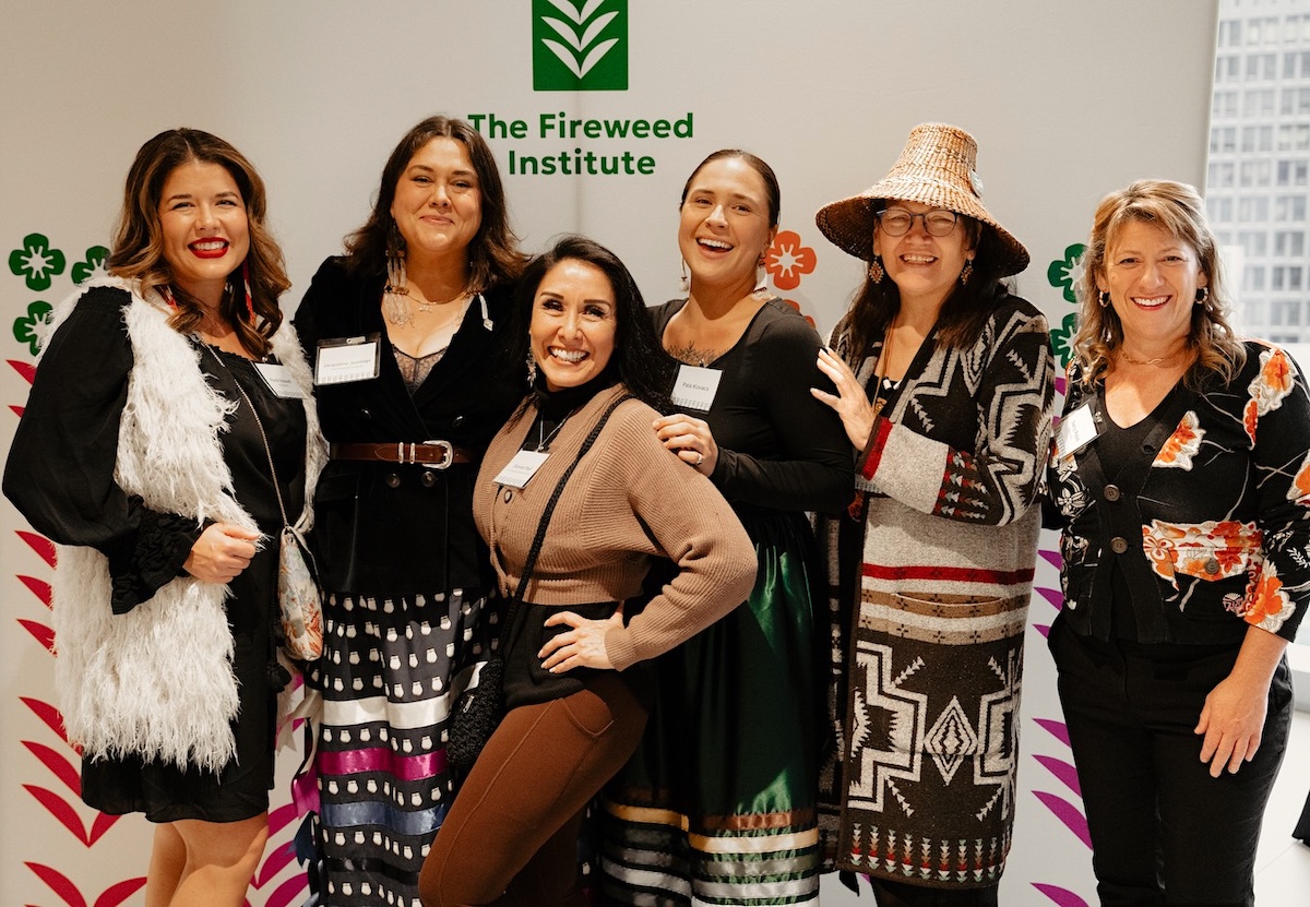 A group of women stand in front of a sign with the words &lsquo;Fireweed Institute&rsquo; written on it.