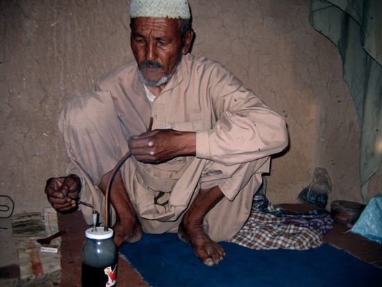 Man smoking opium through water pipe.